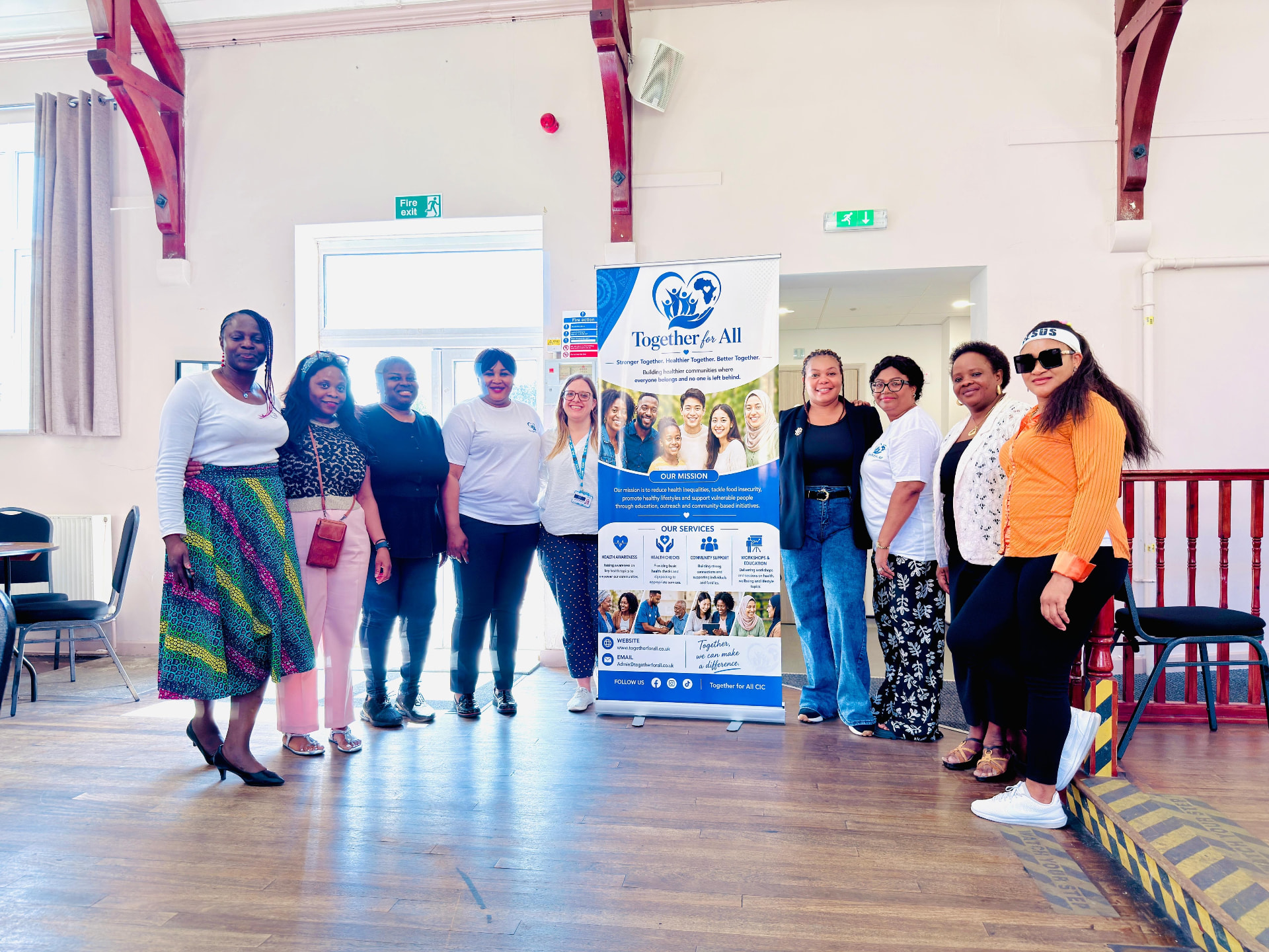 Together For All CIC team beside their banner at a community outreach event