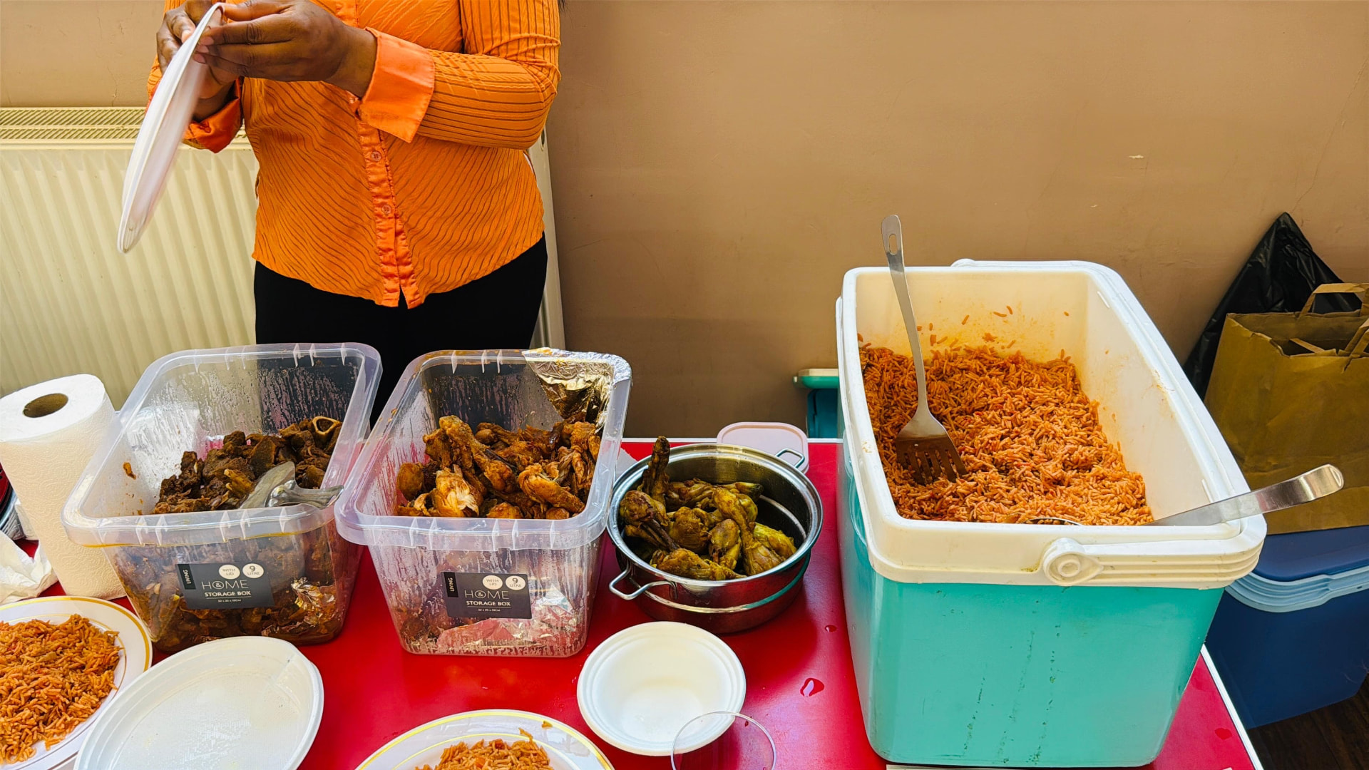 Trays of jollof rice and chicken served at a community meal